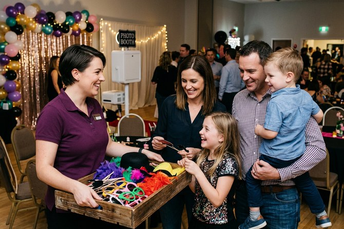 Photo booth attendant helping guests choose props